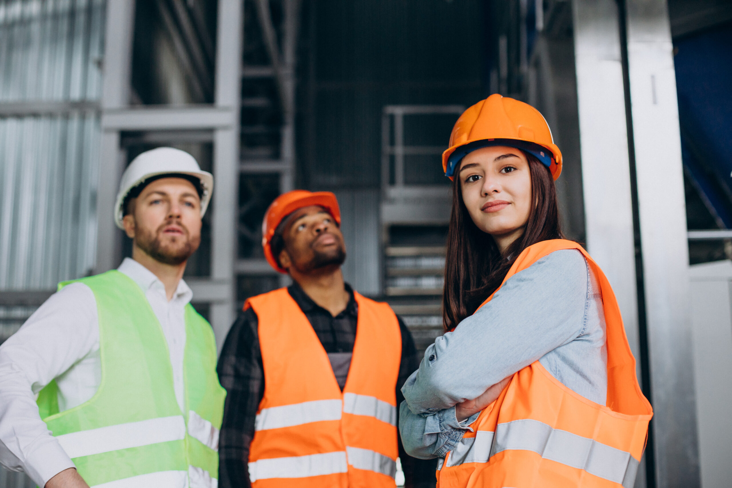 Three factory workers in safety hats discussing safety procedures